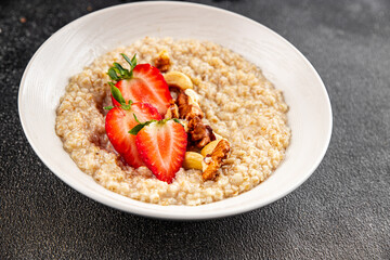 Oatmeal porridge with strawberries and nuts healthy breakfast appetizer dish fresh gourmet food background on the table rustic food top view copy space keto and paleo diet vegetarian and vegan food