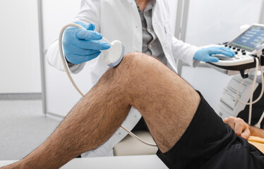 Sonography of knee joint. Male patient with knee injury during knee ultrasound with professional...