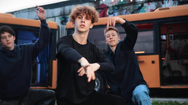 Male dancers voguing intensely in streetwear, executing bold choreography beside orange bus, displaying raw urban performance energy