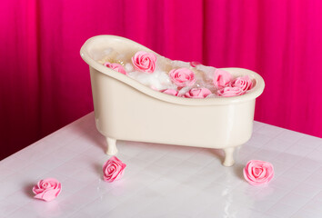 Creative spa card. Miniature bath tub with pink roses on a background of white tiles and pink...