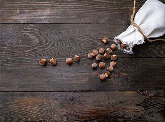 Hazelnuts in a canvas bag on a wooden table.