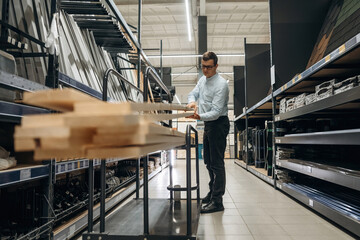 Fototapeta premium Wooden planks. Male hardware store worker in indoors