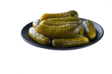 pickled cucumbers on a black plate isolated on a white background.