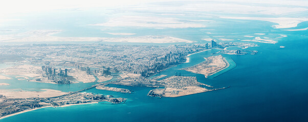 Stunning aerial view of Abu Dhabi, featuring modern skyscrapers, turquoise sea, and vast desert landscape, creating a captivating contrast