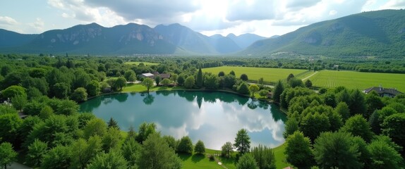 Obraz premium Aerial perspective of a serene pond encircled by vibrant mountains and trees.