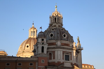 Obraz premium The domes of the Church of the Most Holy Name of Mary and Santa Maria di Loreto rise gracefully under a clear blue sky
