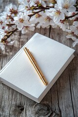 Fototapeta premium A minimalistic mindfulness journal with a gold pen placed on top, surrounded by blooming cherry blossoms on a rustic wooden surface
