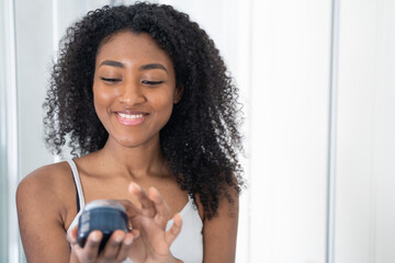 One black woman taking care of her skin with a face cream