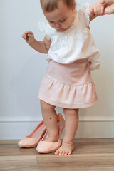 Little girl trying on her mother's pink high heels shoes