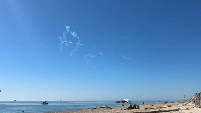 Beach Skywriting Heart and Shapes Over Ocean With Boats and Tourists