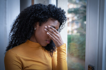 One black woman depressed in front of window
