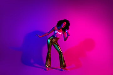 Young stylish woman singing with happiness and energy on a vibrant neon-lit stage with a glowing colorful background