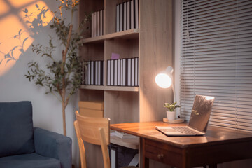 Asian businesswoman taking notes on a sticky note while reviewing a summary report on her computer in the office, focused on improving efficiency and productivity