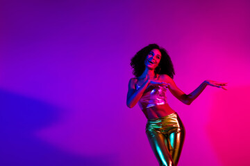 Trendy young woman dancing in neon lighting with vibrant colors