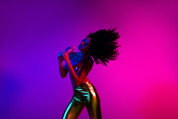 Young woman singing passionately under vibrant neon lights in a night club setting