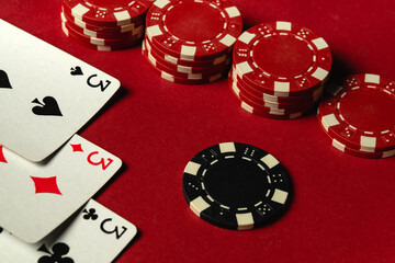 A group of red and black poker chips are displayed next to three of a kind or set of playing cards. The red surface suggests a vibrant gaming night atmosphere, perfect for the excitement