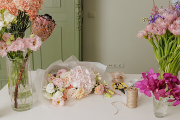 Beautiful floral bouquet wrapped in elegant paper, surrounded by tools and ribbons, ready for gifting or special occasion. flower shop