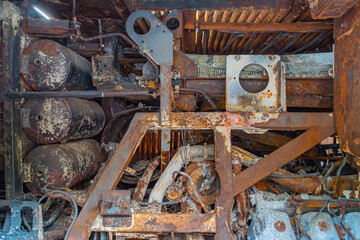 Close-up view of an aged, industrial scene with rusted metal structures and components The image features cylindrical pipestanks, smaller parts, holes, notches, uneven lighting, shallow focus, and