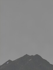 A misty mountain peak enveloped in a soft gray haze, creating a dramatic and mysterious atmosphere. Perfect for those who appreciate moody and ethereal landscapes.