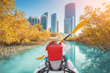Woman paddling in kayak exploring mangrove park in Abu Dhabi, United Arab Emirates