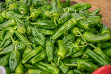 A large pile of fresh green hot peppers on a market stall. Vegetables for sale. Vegetarian product
