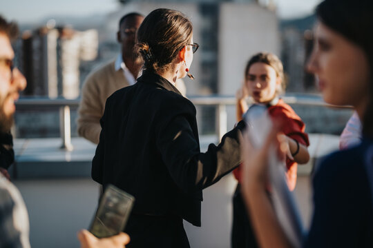 A diverse group of business people celebrates on a high-rise balcony during sunset. The mixed cultural backgrounds highlight inclusivity and teamwork in a dynamic urban setting.