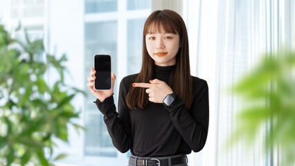 スマートフォンを指差す女性・ビジネスウーマン