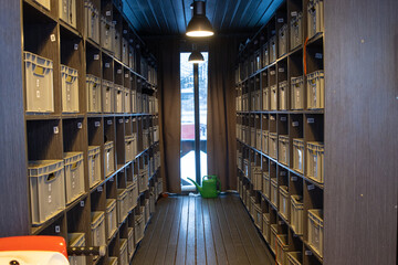 Narrow storage room with numbered boxes and watering can