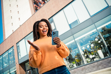 Photo of cute excited girl dressed orange sweatshirt textig social network modern gadget walking...
