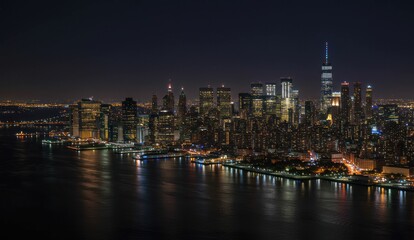 Obraz premium New York City skyline at night with illuminated buildings and waterfront view.