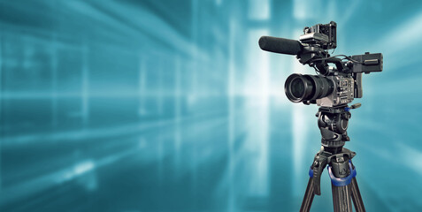 video camera on tripod with modern blue background for broadcast banner with copy space