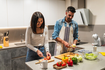 Happy couple preparing vegetables in modern kitchen