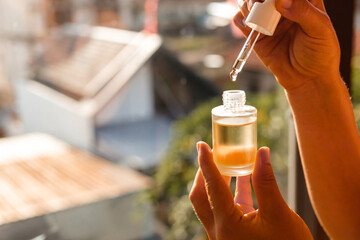 Bottle of natural oil for face and hair care against the background of the morning sun and rays....