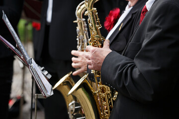Musicians playing saxophones at a street festival in a vibrant outdoor setting during the evening