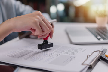 Close-up of hand using a red stamp on a legal document, indicating confirmation or validation in administrative work.