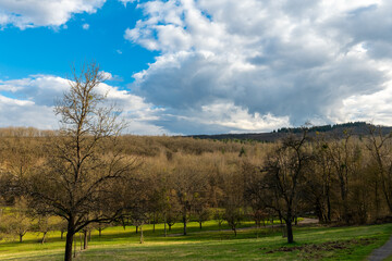 Obraz premium Scenic landscape showcasing rolling hills and dramatic cloud formations under a late afternoon sky