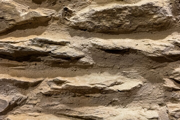 Texture of weathered rock formation showcasing layers and grooves in natural setting under daylight