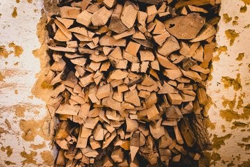 Stacked firewood against a rustic wall showcasing natural wood tones in a cozy setting