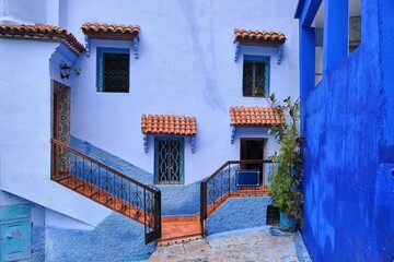 Beautiful house facade of different shades of blue with orange steps and tiled window awning, Chefchaouen, Morocco