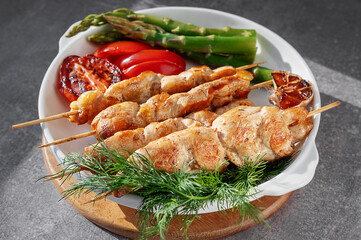 Grilled chicken kebabs with fresh vegetables and herbs on a white plate. Grilled kebabs.