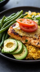 Delicious baked chicken with yellow rice, fresh vegetables, and avocado for a satisfying meal
