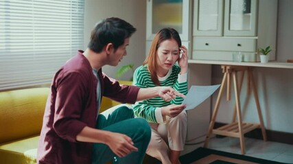 Financial strain testing relationship bond as Asian couple arguing intensely over mounting bills and paperwork within cramped living room environment - Powered by Adobe