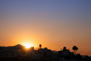 first rays of the sunrise in a mountain on the coast of Malaga, Spain. The summer sky is clear and has sunset colors. There is vegetation in your skirt and the sky is pink and blue in pastel tones © LaMorenita