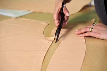 Dressmaker cutting dress fabric on sketch line with sewing machine. Fashion designer tailor or sewer in workshop studio designing new collection clothes. Business owner