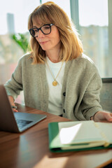 Blond haired businesswoman sitting in a modern office and using her laptop