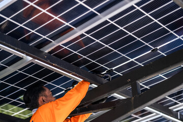 A technician in an orange safety jacket working on the wiring and connections of a solar panel...