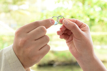 Close-up of a newlywed couple's hands, showing off their rings. The bride joins her ring with the...