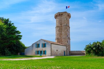 A stunning stone watchtower reaches for the blue sky, proudly showcasing the French flag at its...