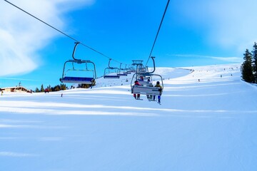 A chairlift carries enthusiastic skiers and snowboarders over a beautiful snow-covered mountain...