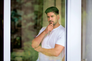 Fototapeta premium Close-up portrait of a handsome man standing by the window